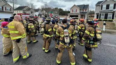 Dress in protective gear, Raleigh Firefighters gather in a neighborhood street to listen to leaders