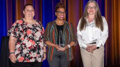 City IT employees Suni Wilkenshoff and Courtney Bland-Fowler accept award from Darlene Garner, VP of Client Services at Tyler.