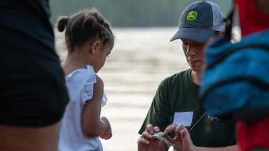 an instructor helping child remove a fish from hook