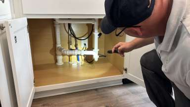 City of Raleigh inspector checking plumbing under kitchen sink for the Home Builders Blitz 2024