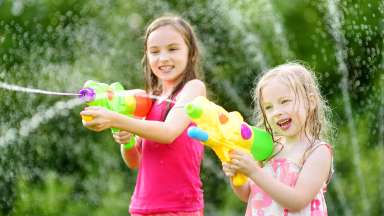 Two girls holding and squirting water with water guns