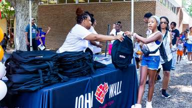 a person giving out a back pack for back to school