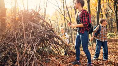 Kids in nature building a shelter with tree branches