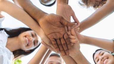 women in a circle with hands in the middle