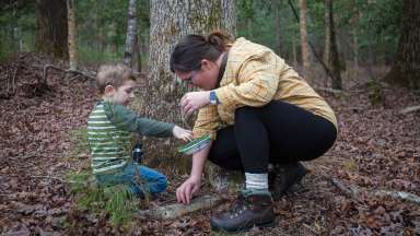 an adult and child in the woods exploring