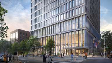 Exterior of glass office tower in the evening with warm glowing light.