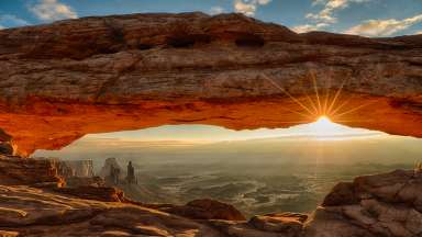 Sunburst under Mesa Arch, with the arches and landscape of Canyonlands National Park appearing under the arch