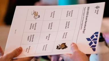 Two hands holding a piece of paper from Raleigh Arts. Paper is &quot;Grant Narrative Bingo&quot;