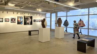 Gallery with several artists work displaying including sculpture, colorful quilts, framed works on paper