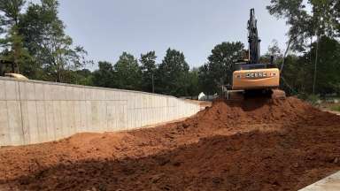 A bulldozer grades land surrounded by trees.