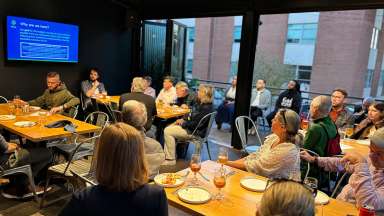 People in a room at a restaurant sitting at tables viewing a presentation on a screen