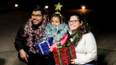 two adults with a child smiling with holiday decorations