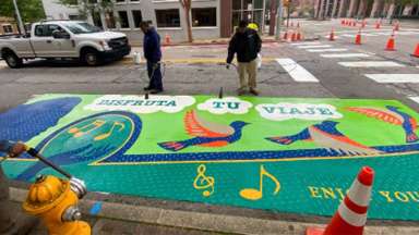 Raleigh Department of Transportation staff use heat to adhere the mural to the pavement