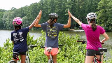 three teens on bikes sharing hi-fives