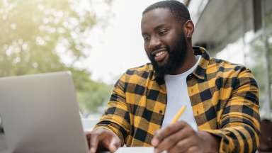 Man taking notes, looking at computer