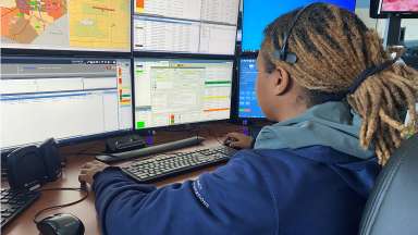 Emergency call taker sits at desk looking at multiple computer screens