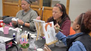 3 people painting with brushes on canvases