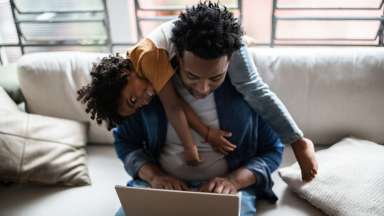 a parent trying to work on a laptop while child plays