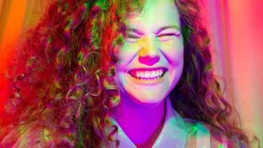 Artist Katie Stewart smiles while illuminated by pink light