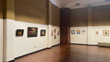paintings hanging in a large room with white walls and a wooden floor