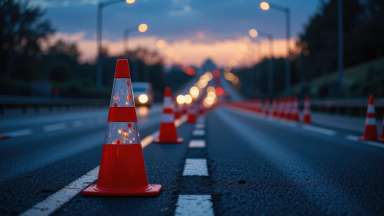 Traffic cones line a highway at dusk creating a lane closure for road maintenance work at night