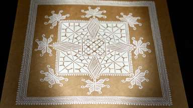 white ink in patterns on brown paper with a bright light on the center of the artwork