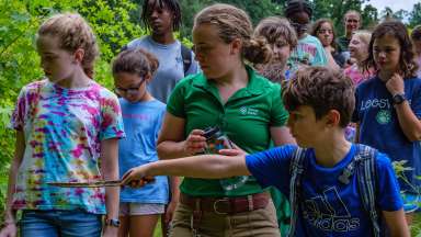 a group outdoors with child pointing at something with a stick