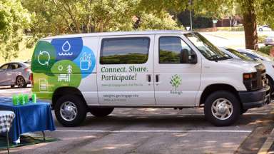 Cargo van with &quot;Connect. Share. Participate&quot; and Raleigh branding parked