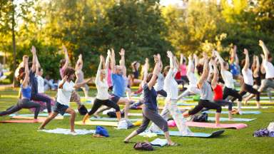 a group of people doing yoga in a park with yoga mats