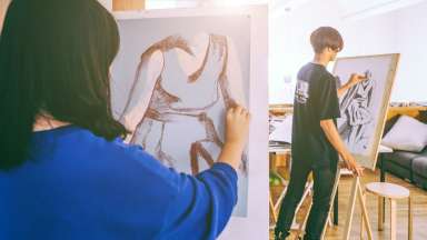 people painting on canvases in an art class