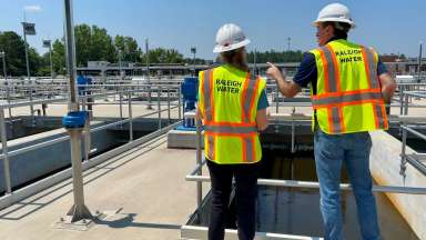 Two workers in yellow safety gear talking to eachother