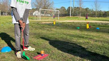 a child with a training golf club practicing putting
