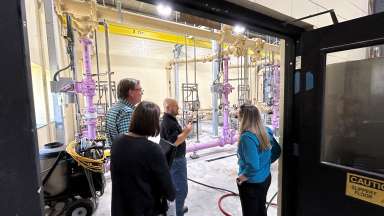 Photo of three people taking a tour of a wastewater plant