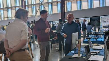 GIS Day event photo from 2024. People talking at participant tables.