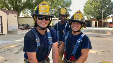 Three firefighters smile wearing RFD Recruit Raleigh helmets