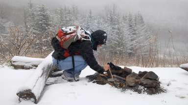 a person in the wilderness building a fire