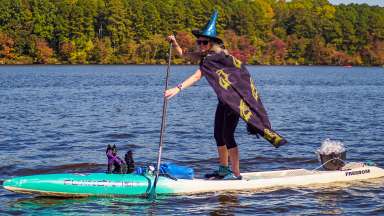 a witch on a lake paddleboarding