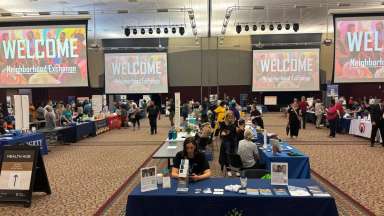 Woman sits behind City of Raleigh table inside an exhibit hall