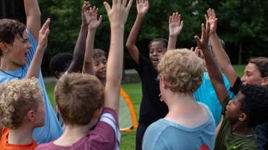 children celebrating by waving their hands in the air as if they do not have a care