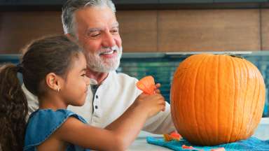 a grandparent and child with a pumpkin