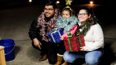 a couple holding a child and holiday gift