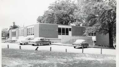 Black and white photo of building with cars in parking lot