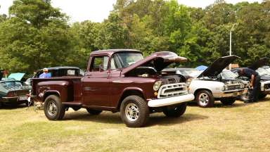 a vintage car show with a burgundy pick-up truck