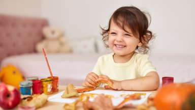happy little child painting autumn leaves