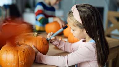 a girl doing crafts on a pumpkin