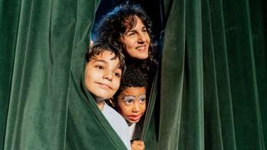 adult and kids behind a theatre curtain