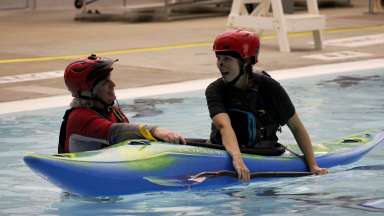 a person in a kayak and an instructor in the pool