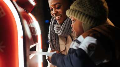 a child and adult putting a letter to Santa in a mailbox