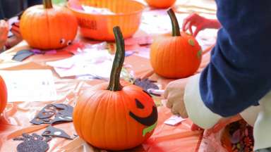 volunteers helping to decorate an orange pumpkin