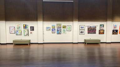 Mix of medium 2-d artworks hanging on a white wall